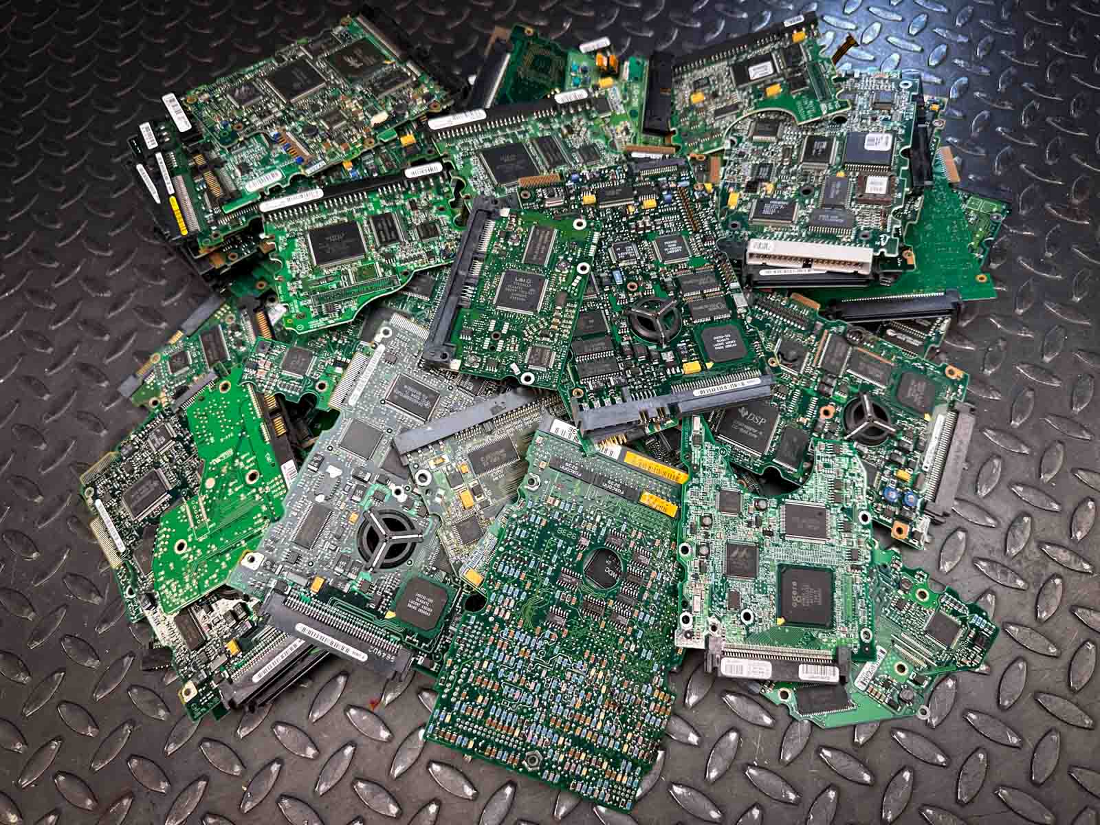 A collection of discarded PCB and hard drive boards from computers, ready for precious metal recovery.